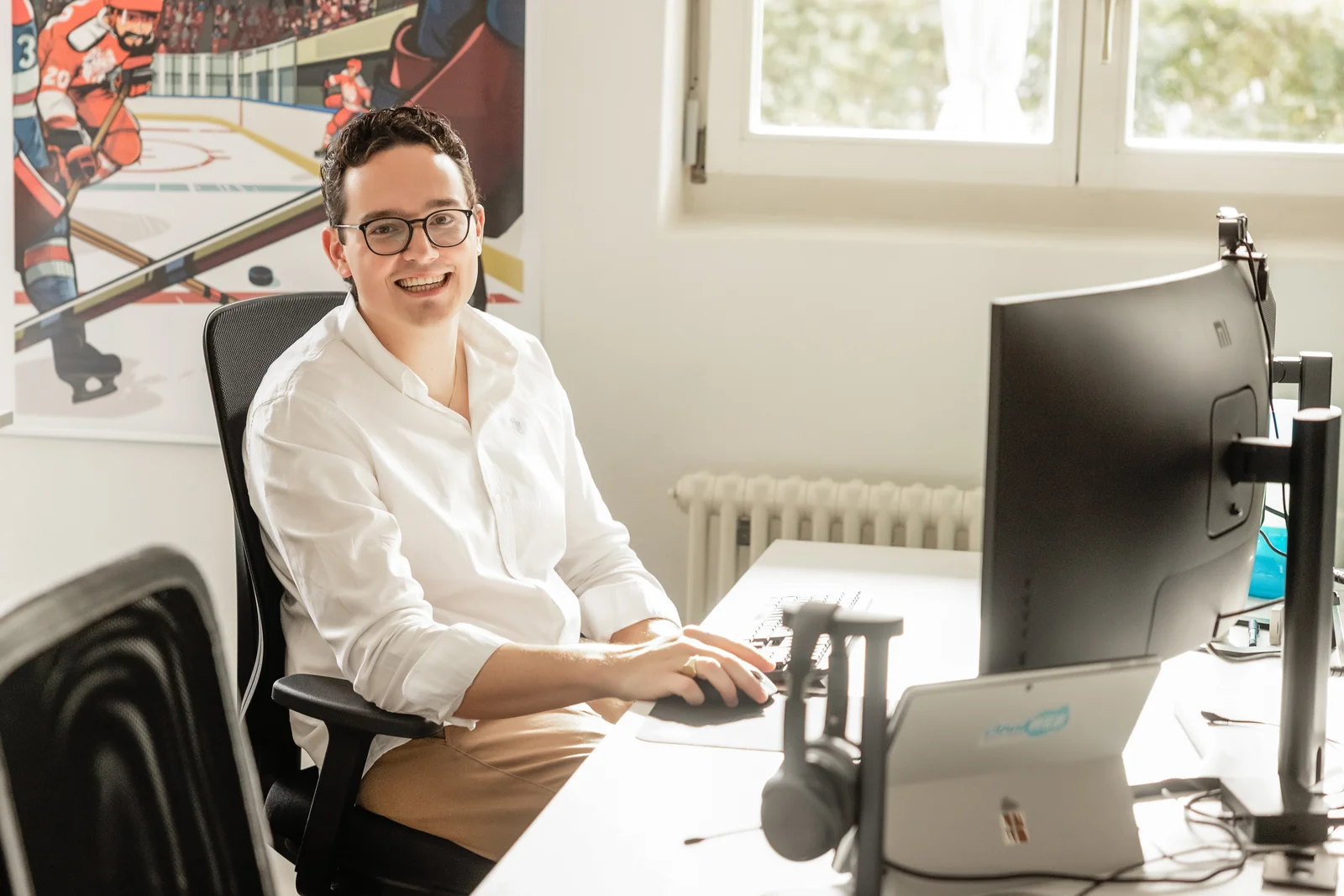 Ein Mitarbeiter von cloudWEB lacht an seinem Arbeitsplatz in die Kamera