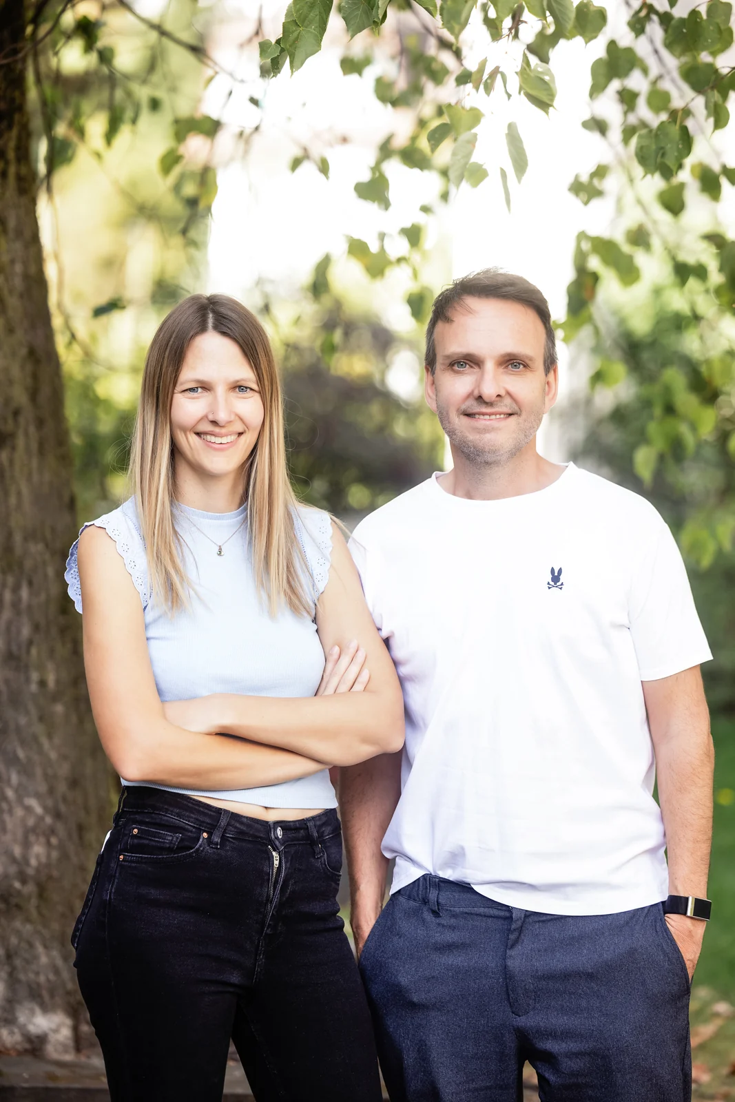 Martina Bernet, Performance & Tracking, und Thomas Hasenfratz, Inhaber & SEO-Spezialist, stehen lächelnd vor einem Baum