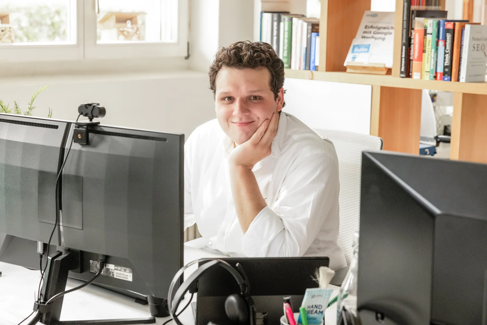 Ein Mitarbeiter von cloudWEB sitzt lächelnd an seinem Arbeitsplatz
