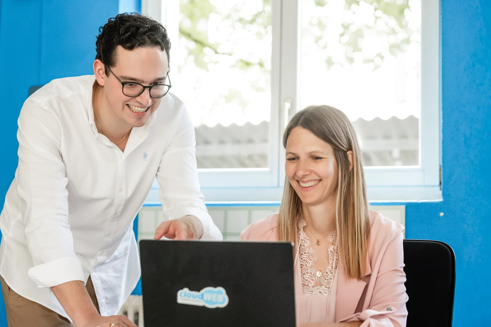 Martina Bernet, Performance & Tracking, und ein Kollege aus dem cloudWEB-Team schauen gemeinsam auf einen Laptop